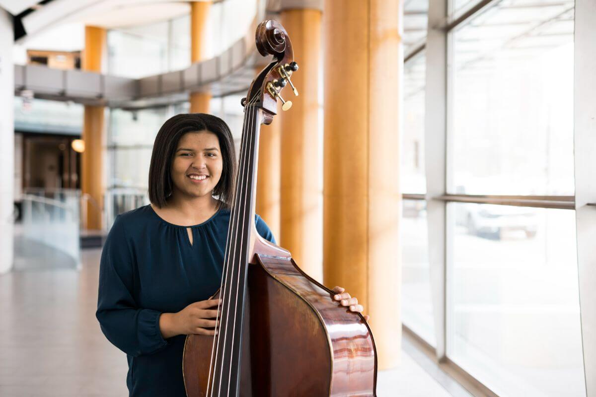 珍妮·加迪，24岁, a double bass major at Eastman and first generation student from Lancaster, PA, is photographed in Eastman 的atre.